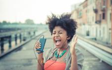 Young woman screaming to music from smartphone
